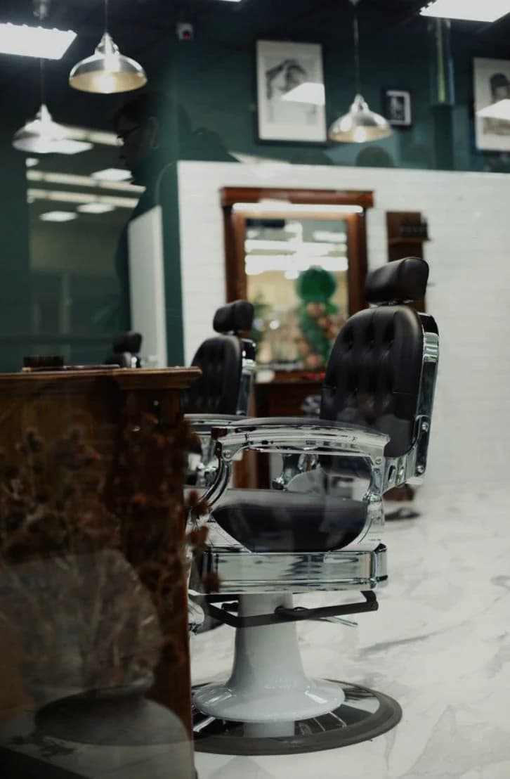 Black leather barber chair in a salon with a marble floor