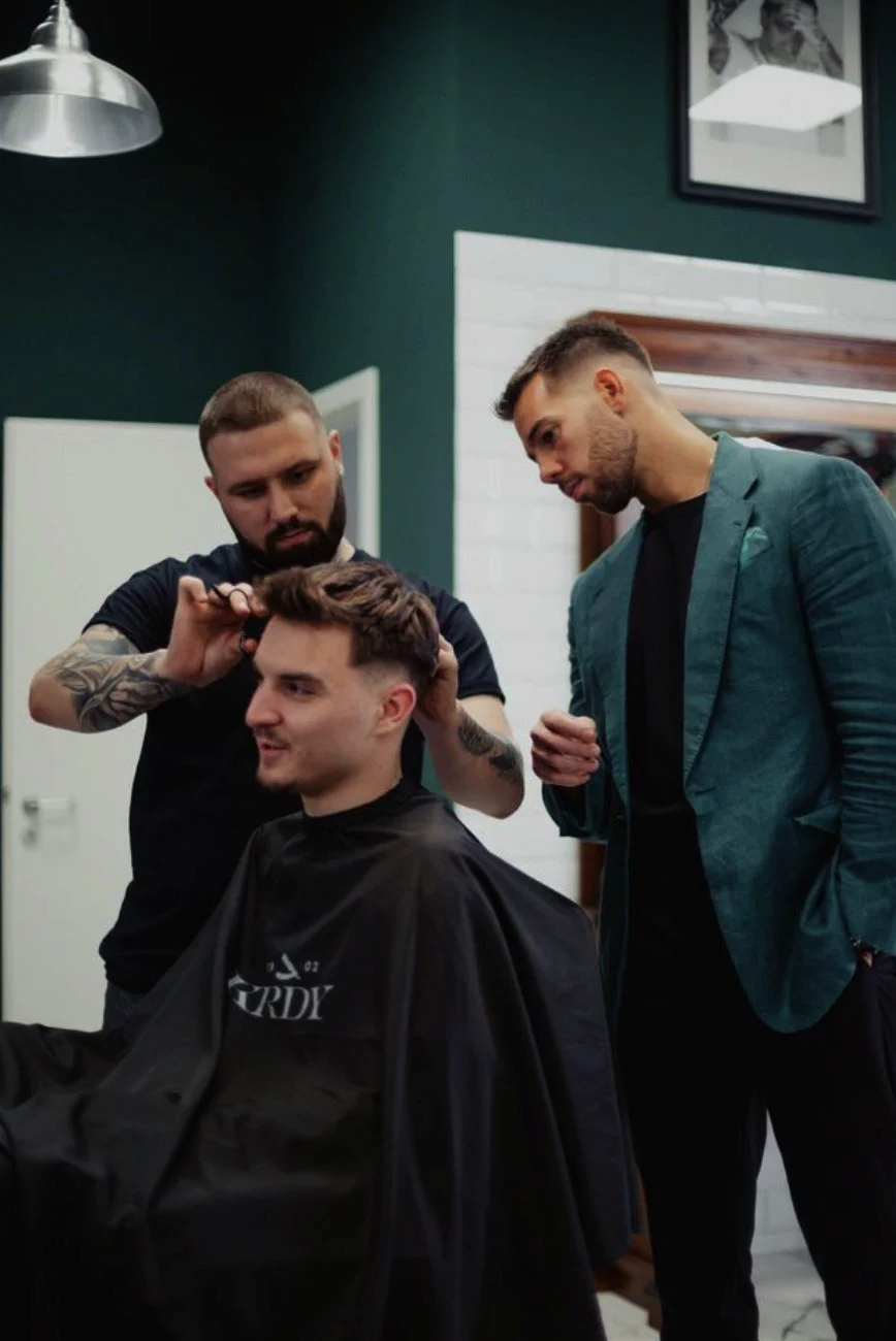 Borbély zöld zakóban vendéget nyír a Koródy Barber Shopban